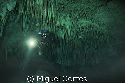 Diver into a big stalactites cave. by Miguel Cortes 